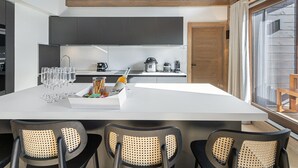 Una cocina moderna con una isla grande, armarios oscuros y techo de madera.