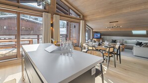 Una cocina amplia con una isla grande, piso de madera y ventanas grandes que ofrecen vistas al exterior.