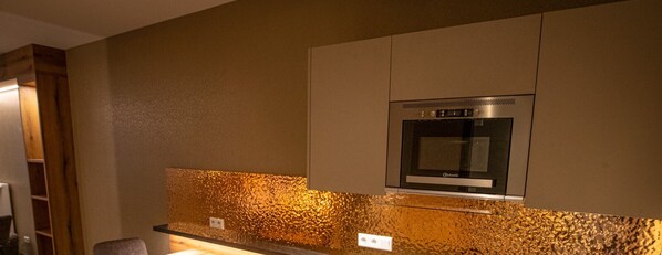 Une cuisine dotée d’un four en acier inoxydable, d’un revêtement mural texturé et de meubles en bois.