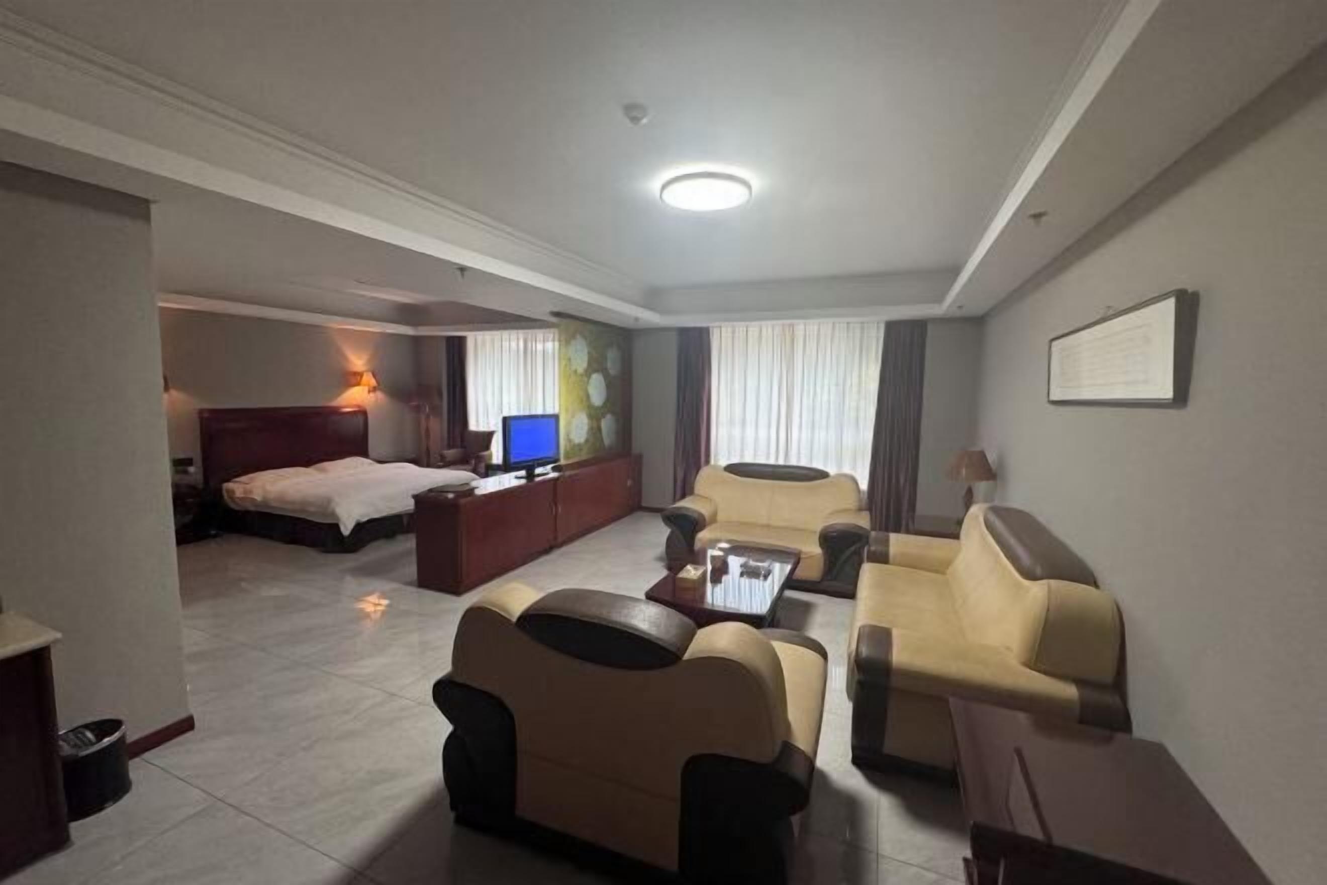 A hotel room with a bed, a TV, a sofa, a coffee table, and a desk.