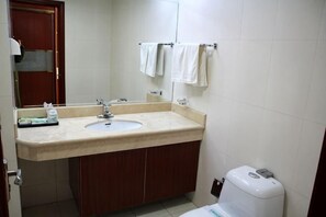 A bathroom with a sink, mirror, towel rack, and toilet.