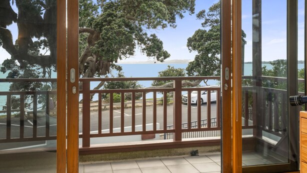 Un balcon donnant sur un parking et des arbres.