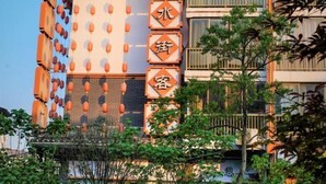 A hotel with multiple floors, a vertical sign with Chinese characters, and a balcony with railings. - Shui Jie Hostel (Xing'an County)