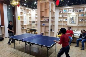 Una mesa de ping pong en una habitación con estantes y libreros.