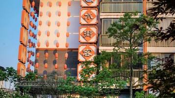 Un immeuble à plusieurs étages, doté d’une enseigne verticale ornée de caractères chinois, de balcons et surplombant un ciel dégagé.