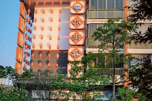 A multi-story building with a vertical sign featuring Chinese characters, balconies, and a clear sky. - Shui Jie Hostel (Xing'an County)