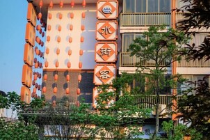 Un edificio de varios pisos con un letrero vertical con caracteres chinos, balcones y cielo despejado.