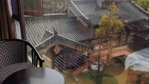 A view from a window with traditional tiled roofs, a chair, and a table. - Shui Jie Hostel (Xing'an County)
