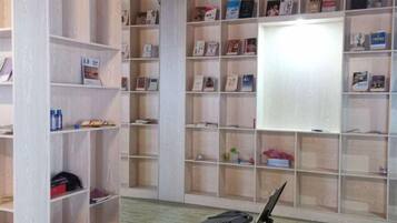 A room with multiple bookshelves filled with books and magazines, a black chair, and a whiteboard on the wall.