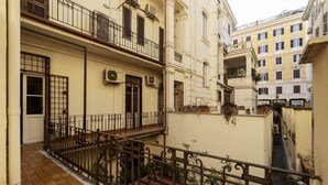A narrow urban street with buildings featuring balconies and air conditioning units.