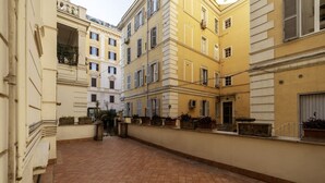 A narrow alleyway with terracotta tiled flooring, flanked by buildings with balconies and windows.