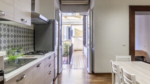 A narrow kitchen with a dining area, a view to the outside, and a small balcony.