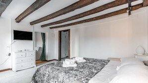 A bedroom with a bed, a dresser, a TV, and a door leading to another room. - GuestHost - The Venice Red Door Aparment (Venezia)