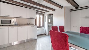 A modern kitchen with white cabinets, a microwave, and a dining area with red chairs. - GuestHost - The Venice Red Door Aparment (Venezia)