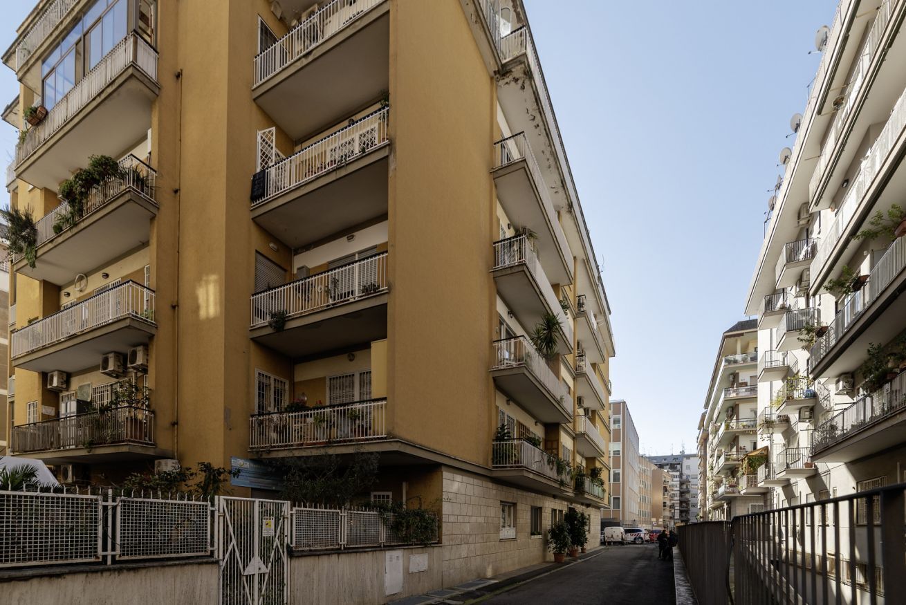 Un immeuble résidentiel à plusieurs étages, doté de balcons, d’une entrée sécurisée et situé dans une rue étroite.