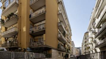 Un immeuble résidentiel à plusieurs étages, doté de balcons, d’une entrée sécurisée et situé dans une rue étroite.