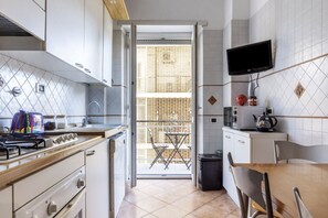 A kitchen with a gas stove, a microwave, a TV, and a dining area with a table and chairs.