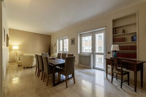 A dining area with a table and chairs, a bookshelf, and a radiator.