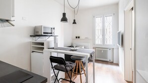 Una cocina compacta con microondas, una pequeña mesa de comedor y taburetes de bar.