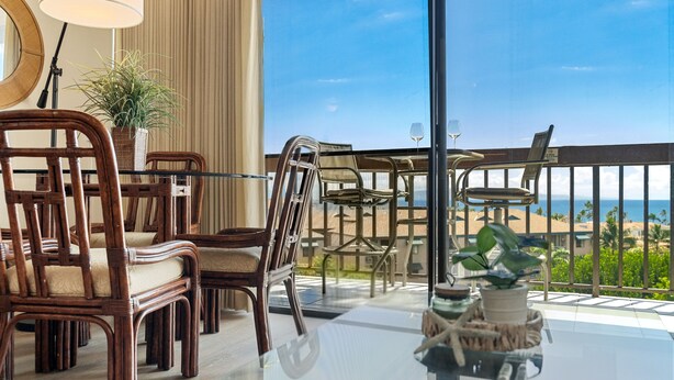 A balcony with wicker furniture, a glass table, and a view of the ocean. - Convenient to downtown Kihei, across famous Charley Young Beach, 3 pool, tennis courts (MV3407) (Kihei)