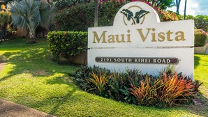 A sign for 'Maui Vista' at 2191 South Kihei Road, surrounded by lush greenery and a palm tree. - Convenient to downtown Kihei, across famous Charley Young Beach, 3 pool, tennis courts (MV3407) (Kihei)