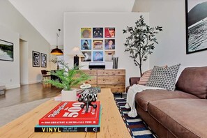 Una sala de estar moderna con una mesa de centro de madera, un sofá de cuero marrón y una planta grande.