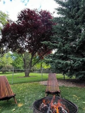 A grassy outdoor area with a fire pit and two wooden chairs. - Stylish 3BR/2BA Home near Park (Boise)