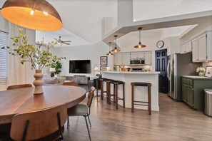 Una cocina moderna con una isla central, taburetes de bar y un comedor con mesa y sillas de madera.