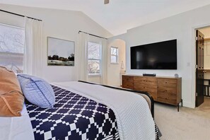 Un dormitorio con cama, cómoda, televisor y ventana.