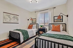 A bedroom with two beds, a world map, a globe, and a window with blinds. - Stylish 3BR/2BA Home near Park (Boise)