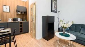 A compact living space with a kitchenette, a dining area, a sofa, and a small table with a vase of flowers.