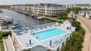 A swimming pool with lounge chairs and a docked boat area. - Stunning Marsh and Bay Views from Beautiful 2 Bedroom Condo (Ocean City)