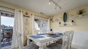 A dining area with a glass table, white chairs, and nautical decor. - Stunning Marsh and Bay Views from Beautiful 2 Bedroom Condo (Ocean City)