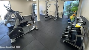 Una palestra con macchinari cardio, attrezzatura per pesi e un tappetino da yoga.