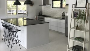 A modern kitchen with a central island, bar stools, a built-in stove, and a pendant light. - Gorgeous Large Home, 5 Mins To Beach, Sunset Views (noosa)