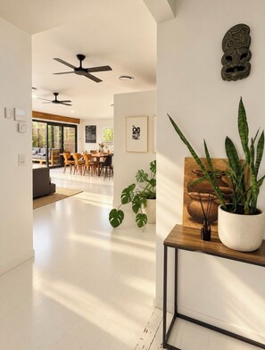 A modern interior with a dining area, ceiling fans, and potted plants.