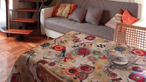 A living room with a grey sofa, a patterned tablecloth, a metal basket, and a staircase with red accents. - La Terrazza Apartment (Catania)