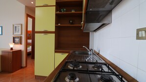 Una cocina con estufa a gas, armarios de madera y salpicadero de azulejos.