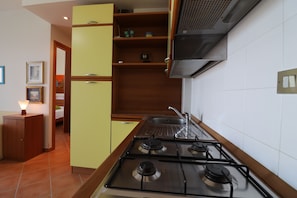 Une cuisine équipée d’une cuisinière à gaz, de meubles en bois et d’un dosseret carrelé.