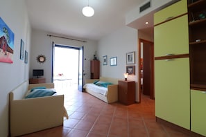 Une pièce comprenant un lit, un canapé, une armoire et un réfrigérateur.