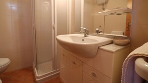 Un baño con ducha, lavamanos e inodoro.