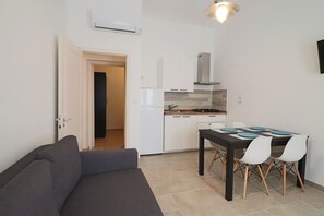 Um espaço compacto com cozinha compacta, mesa de jantar com cadeiras e sofá.