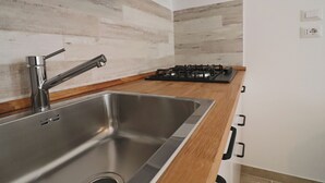 Una cocina moderna con un lavamanos de acero inoxidable, encimera de madera y una estufa a gas.