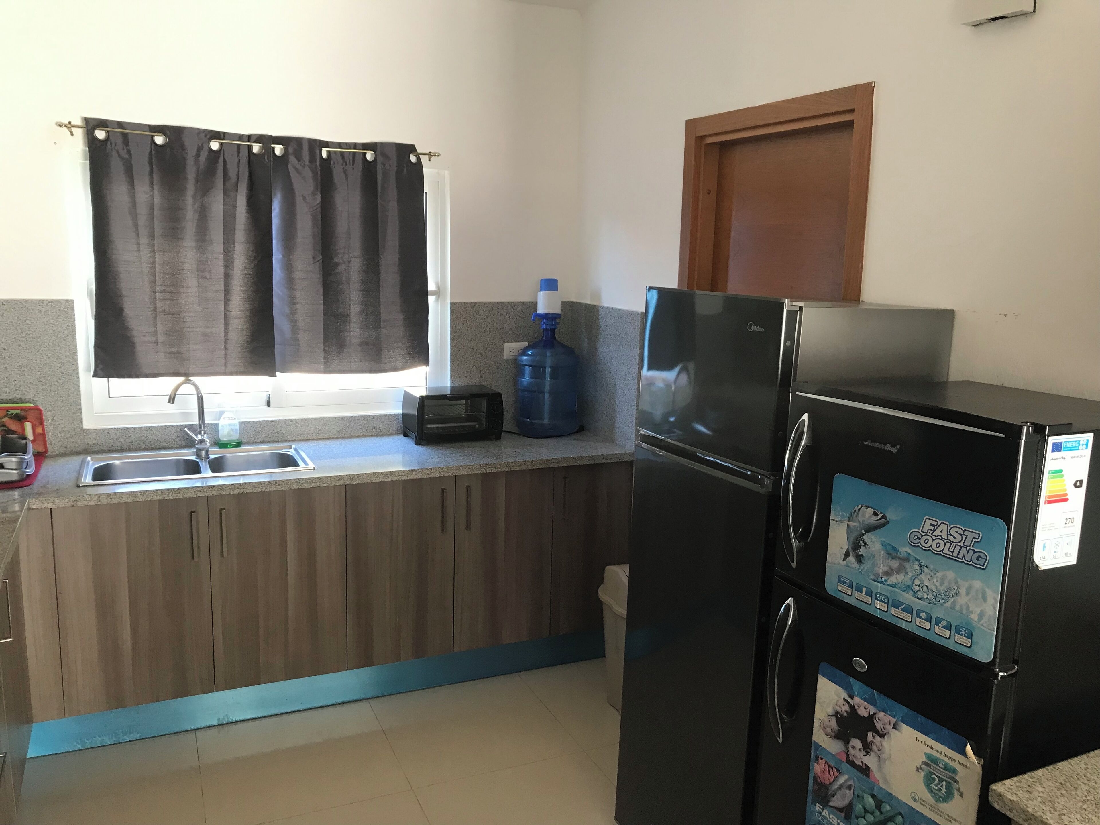 A kitchen with a sink, a toaster, a refrigerator, and a water dispenser.