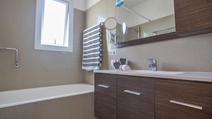 A modern bathroom with a bathtub, a vanity with a mirror, and a towel rack. - Protaras holiday villa - rentprivatevillas 174 (Protaras)
