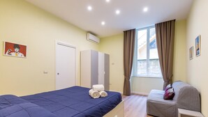 A bedroom with a bed, a sofa, a wardrobe, and a window with curtains.