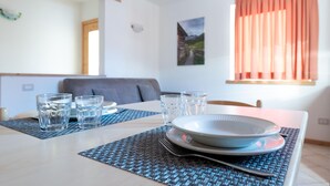 Une table à manger dressée avec des verres, des assiettes et une fourchette, le tout posé sur un set de table en fibres tressées.