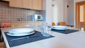 Une cuisine moderne équipée d’un four à micro-ondes, de placards et d’une table à manger avec des assiettes et des verres.