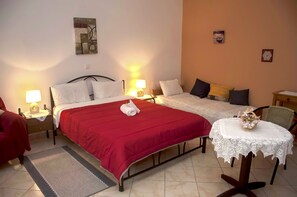 Relax in this inviting room featuring a large bed, a smaller bed, and a comfortable chair.
