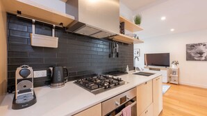 A modern kitchen with a black tiled backsplash, stainless steel appliances, and wooden cabinets. - Modern 1 Bedroom Apartment in Brunswick East Near CBD (Brunswick East)